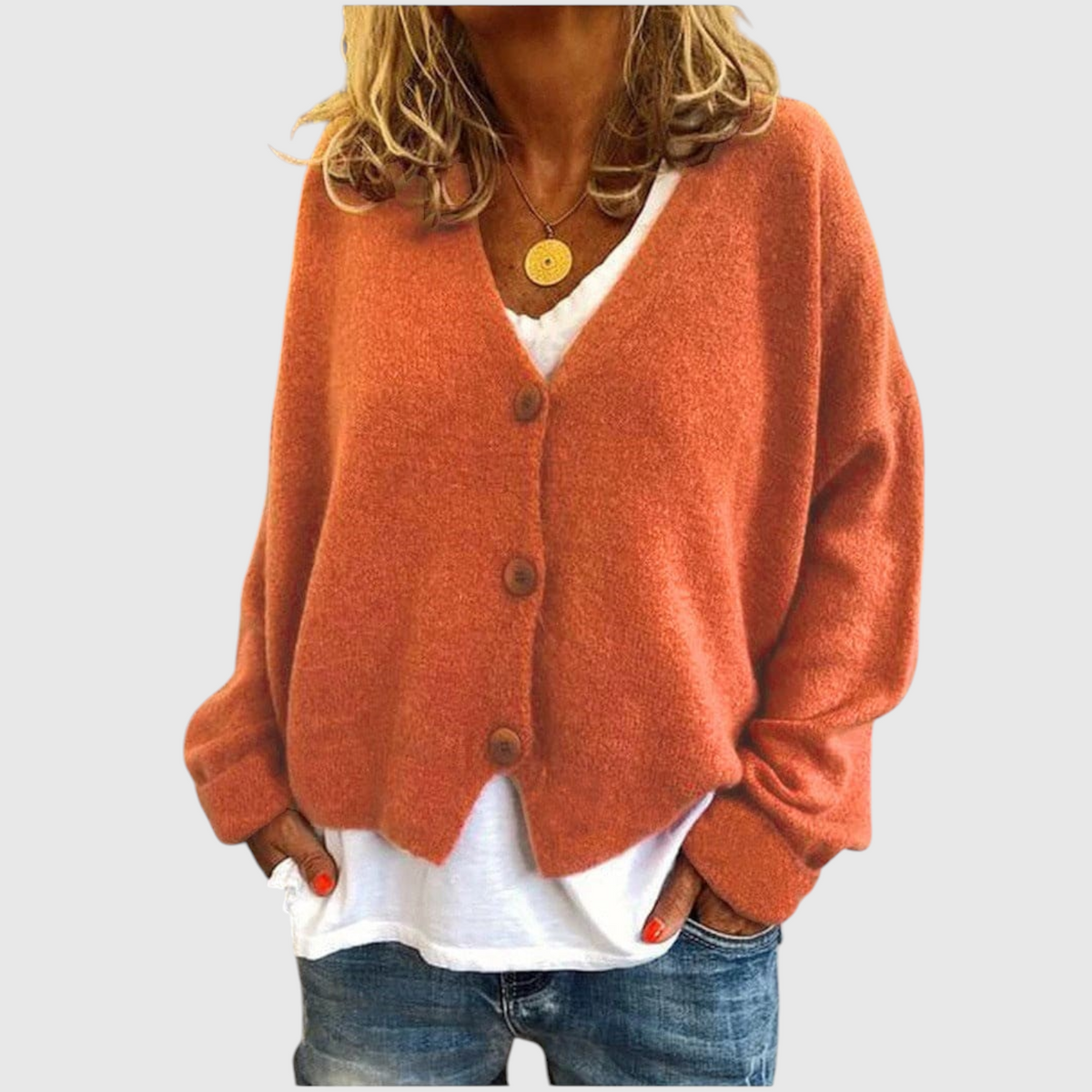Frau trägt orangefarbene Strickjacke mit V-Ausschnitt und Knopfleiste über weißem Shirt und Jeans_0