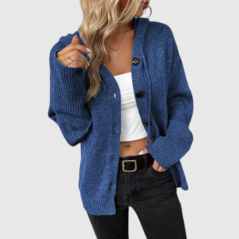 Frau trägt eine blaue gerippte Strickjacke mit Knopfverschluss über einem weißen Top und schwarzer Jeans._0