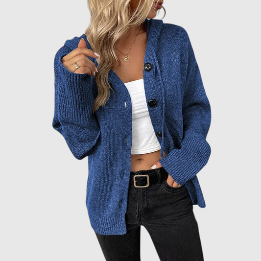 Frau trägt eine blaue gerippte Strickjacke mit Knopfverschluss über einem weißen Top und schwarzer Jeans._0