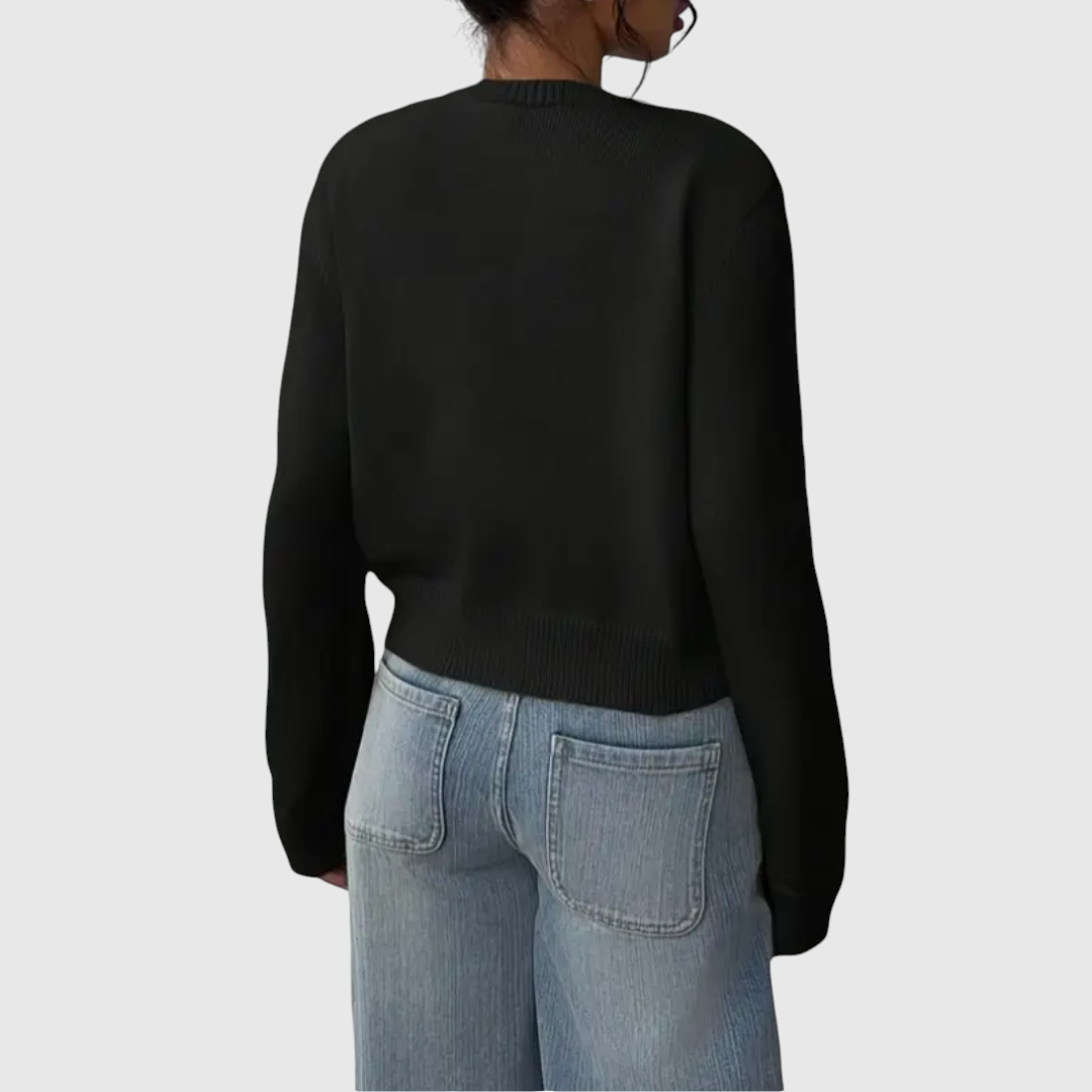 Modell trägt eine kurz geschnittene Strickjacke mit Rundhalsausschnitt und Knopfleiste über einem weißen Top und heller Jeans._10