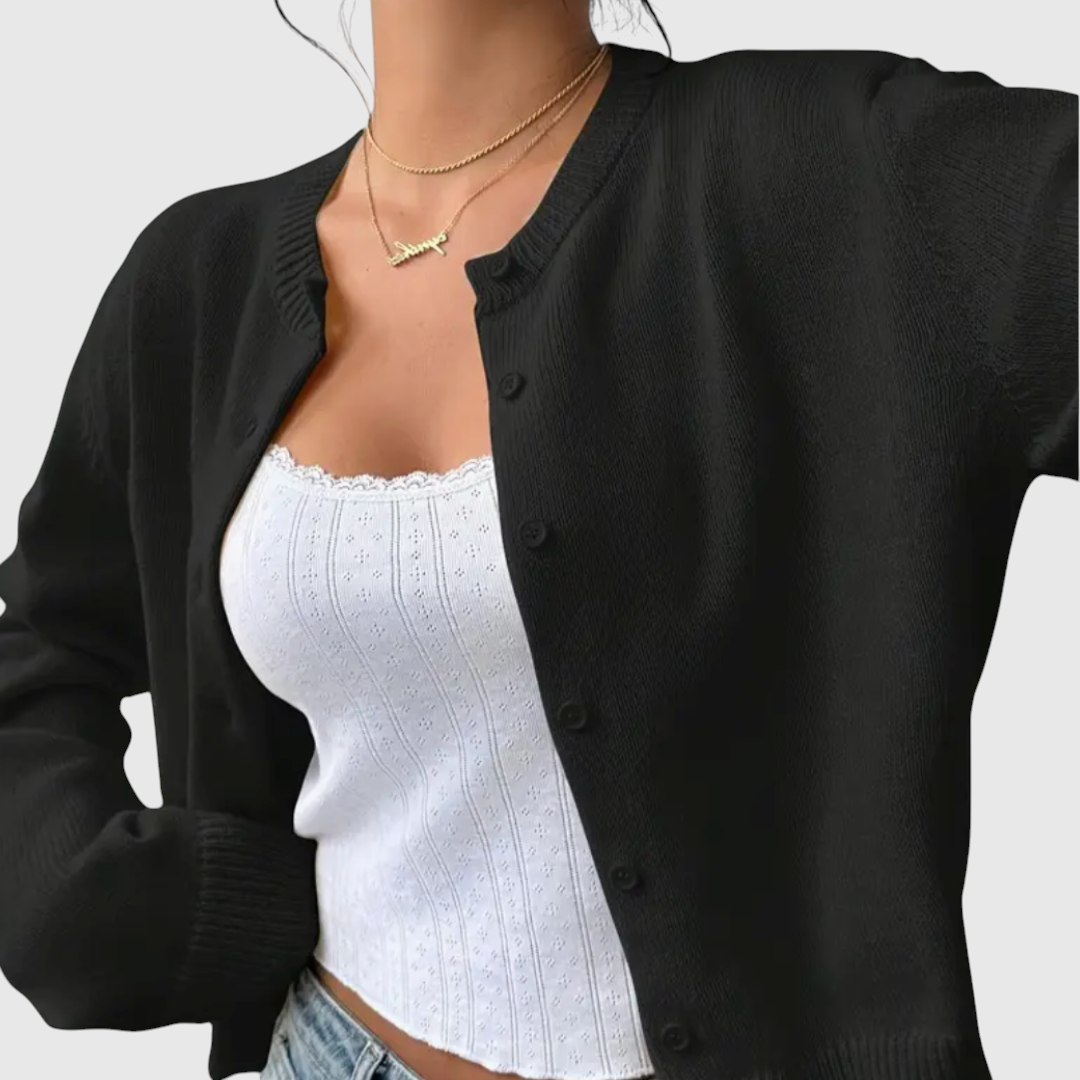 Modell trägt eine kurz geschnittene Strickjacke mit Rundhalsausschnitt und Knopfleiste über einem weißen Top und heller Jeans._11