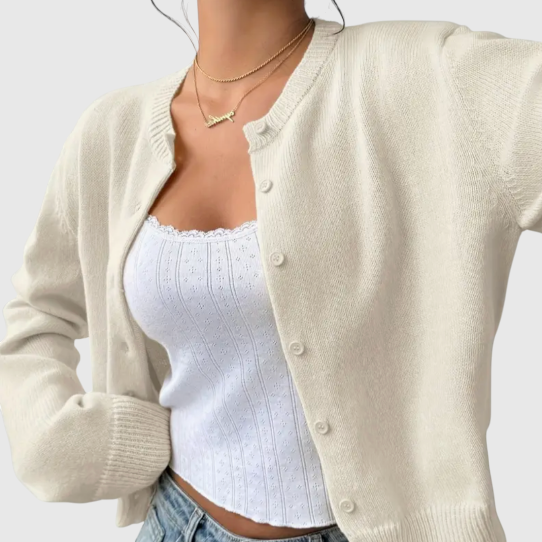Modell trägt eine kurz geschnittene Strickjacke mit Rundhalsausschnitt und Knopfleiste über einem weißen Top und heller Jeans._2