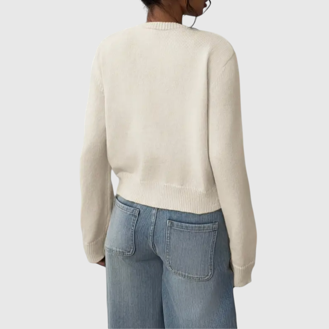 Modell trägt eine kurz geschnittene Strickjacke mit Rundhalsausschnitt und Knopfleiste über einem weißen Top und heller Jeans._3