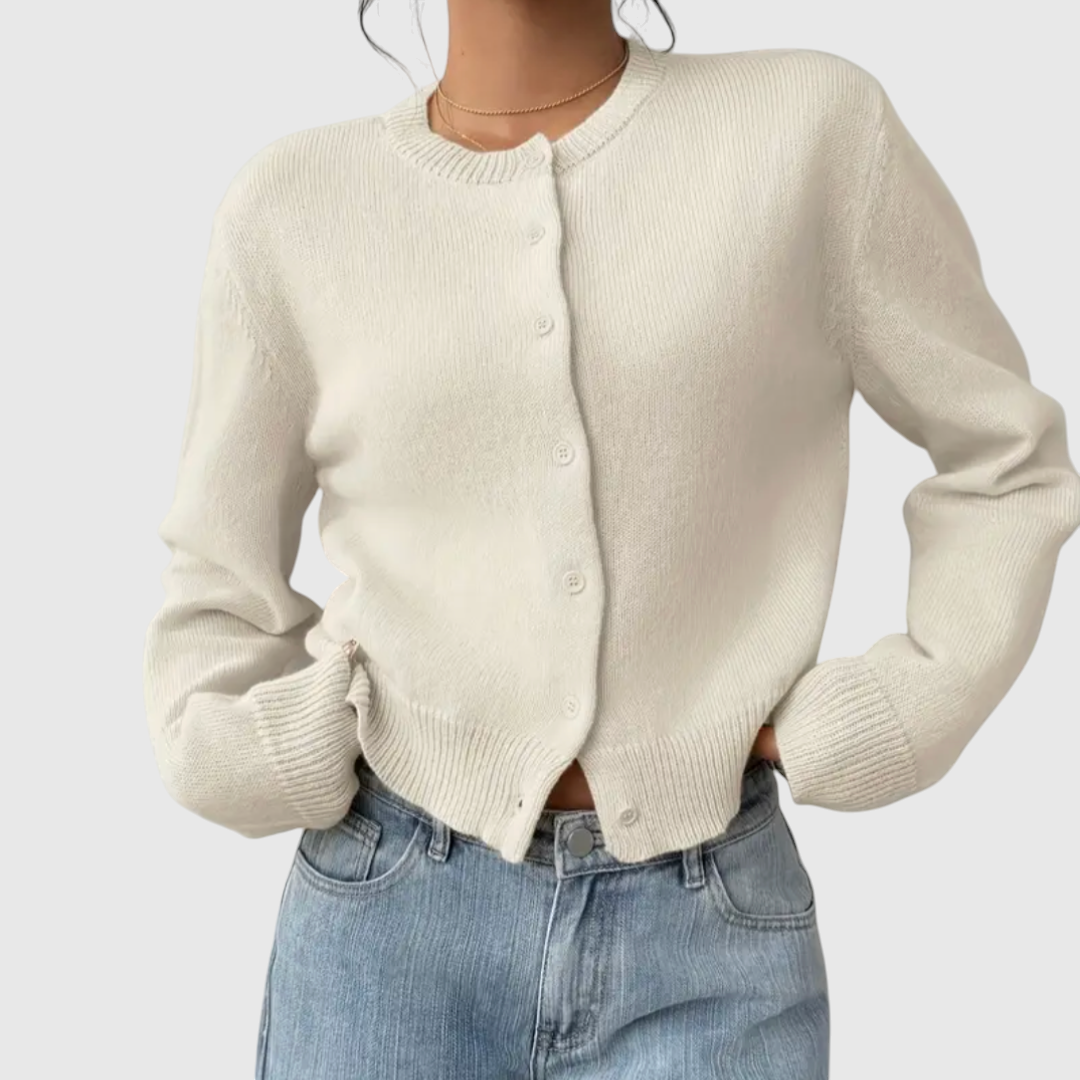 Modell trägt eine kurz geschnittene Strickjacke mit Rundhalsausschnitt und Knopfleiste über einem weißen Top und heller Jeans._4