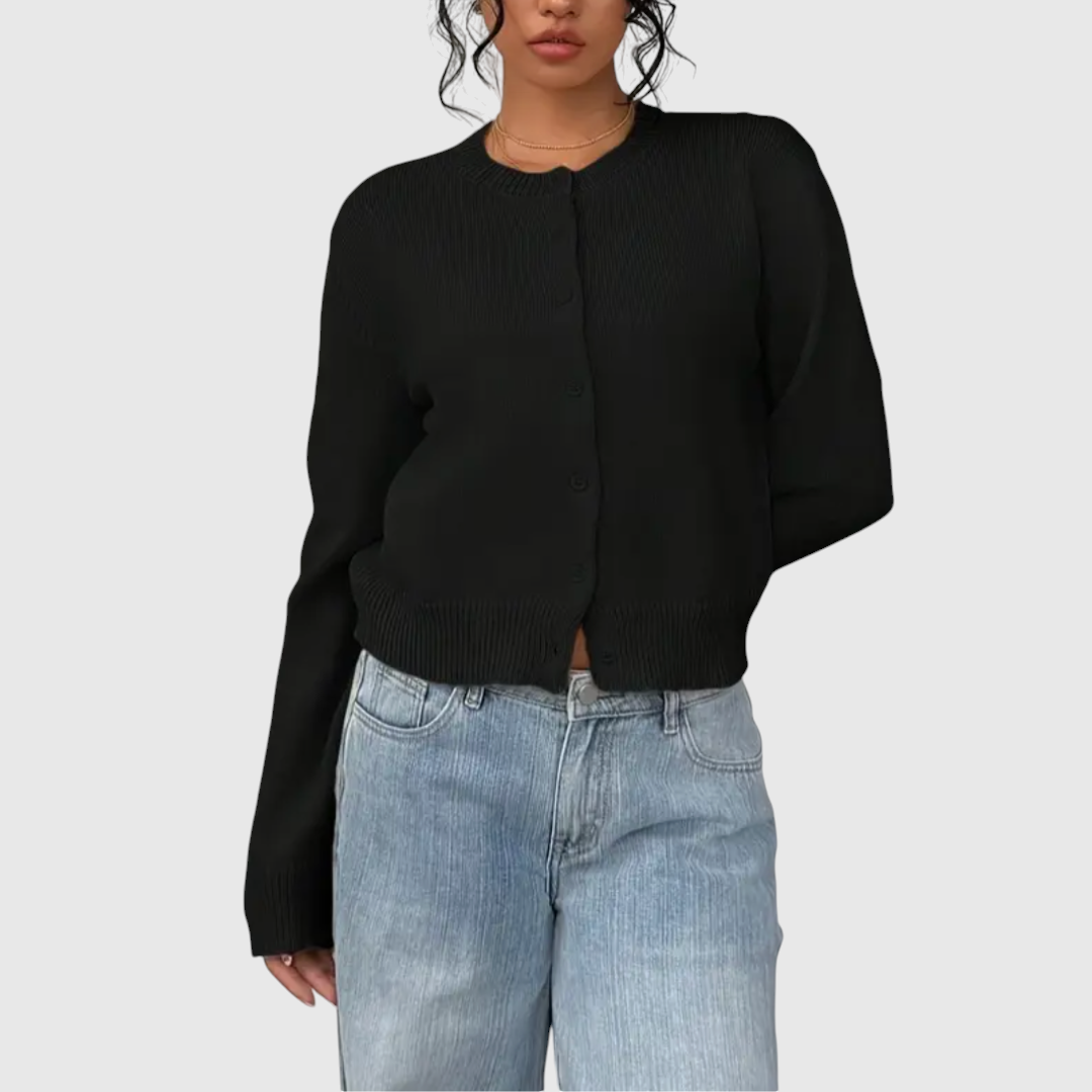 Modell trägt eine kurz geschnittene Strickjacke mit Rundhalsausschnitt und Knopfleiste über einem weißen Top und heller Jeans._9